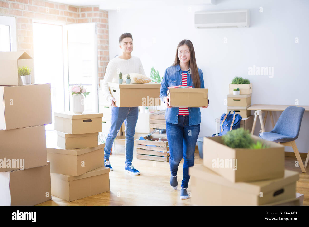 Beautiful young asian couple looking happy holding cardboard boxes ...