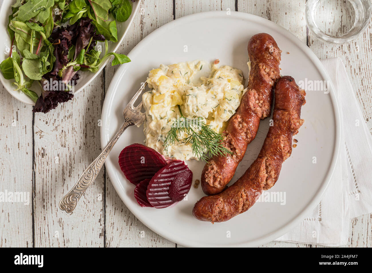 Isterband sausage with dill stewed potatoes and pickled beetroots, traditional Swedish food. On a white wooden table, flat lay seen from above. Stock Photo