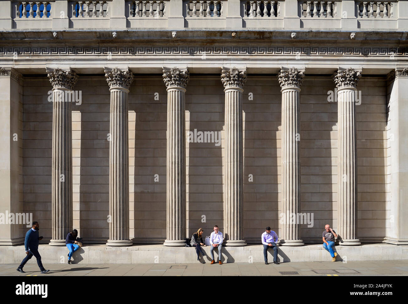 London, England UK. People sitting outside the Bank of England - Corinthian columns Stock Photo