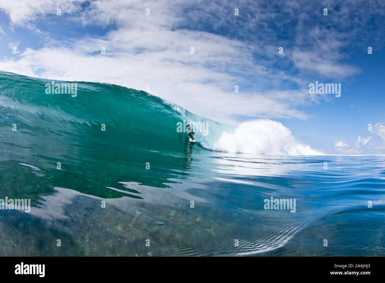 Surfer surfing tube barrel section of the big crushing wave in crystal clear water in Mentawai islands, Indonesia Stock Photo