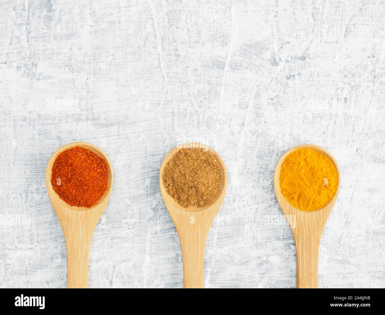 Spices help maintain good health and improve appetite, top view on white concrete background. Red chili pepper, masala, turmeric in wooden spoon. Mode Stock Photo