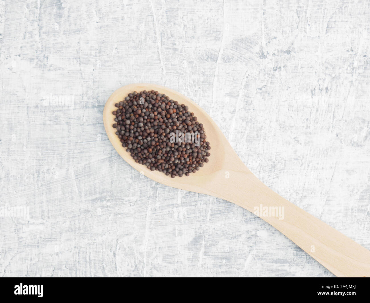 Spices and herbs help maintain good health and improve appetite, top view on white concrete background. Mustard seeds in wooden spoon. Modern apotheca Stock Photo