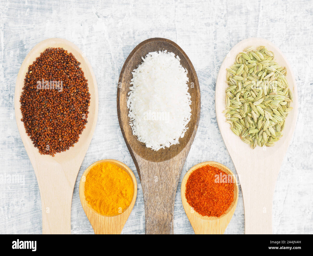 Spices and herbs set on concrete background in wooden spoon. Turmeric, fennel, mustard, chili pepper, masala. Modern apothecary, naturopathy and ayurv Stock Photo