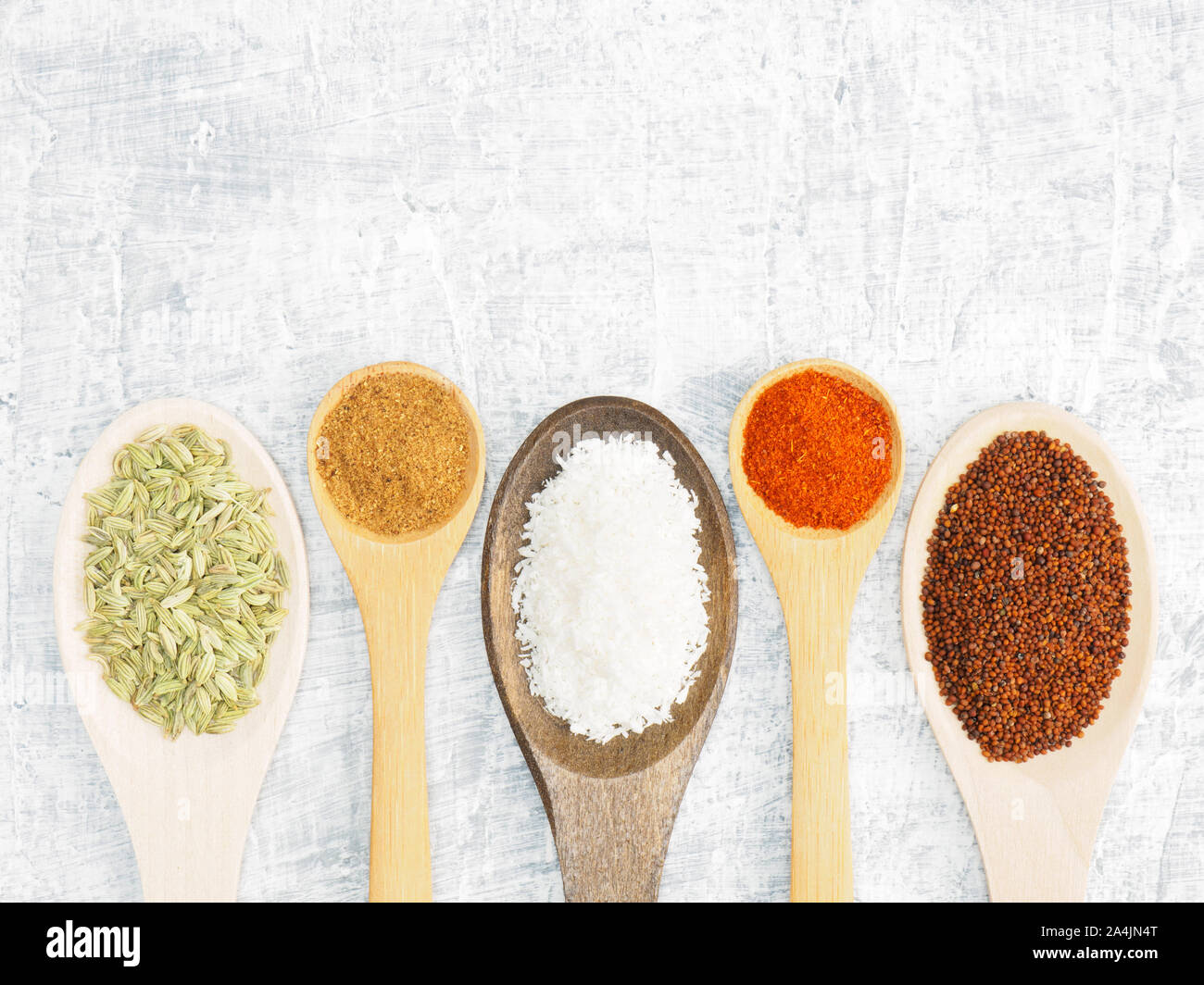 Spices and herbs set on concrete background in wooden spoon. Fennel, mustard, chili pepper, masala. Modern apothecary, naturopathy and ayurveda concep Stock Photo
