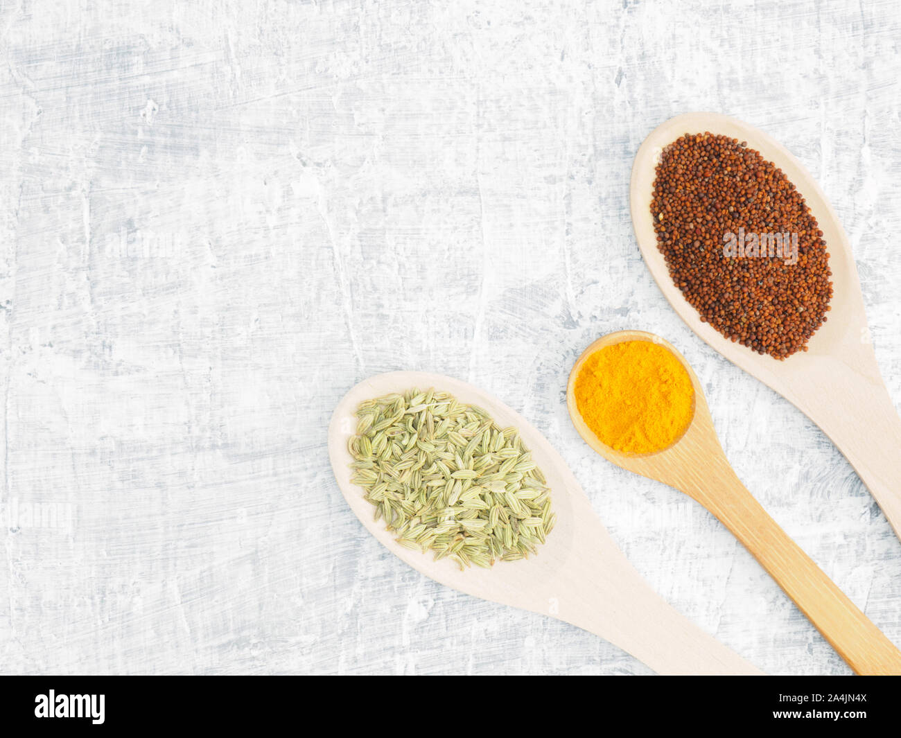 Spices and herbs set on concrete background in wooden spoon. Fennel, mustard, turmeric. Modern apothecary, naturopathy and ayurveda concept. Stock Photo