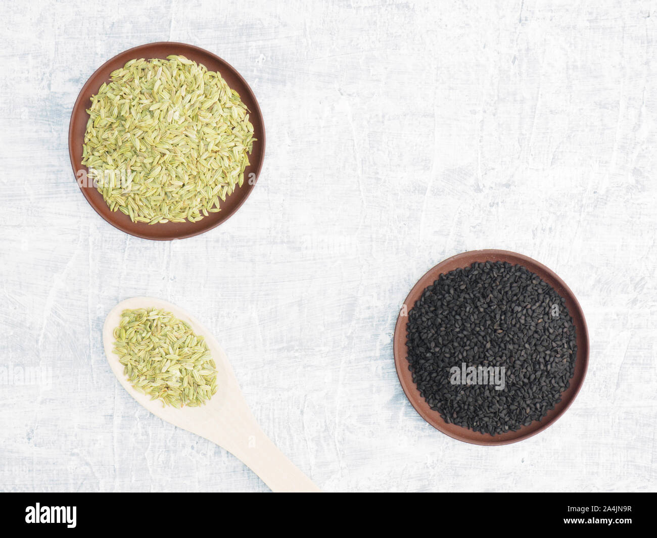 Spices and herbs set on concrete background in clay plate and spoon. Black cumin and fennel. Modern apothecary, naturopathy and ayurveda concept. Stock Photo