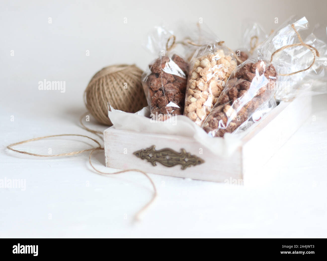 Close up of variety of nuts and cereal in rustic wooden box on a white background. Healthy dry breakfast for children with space for text. Homemade Stock Photo