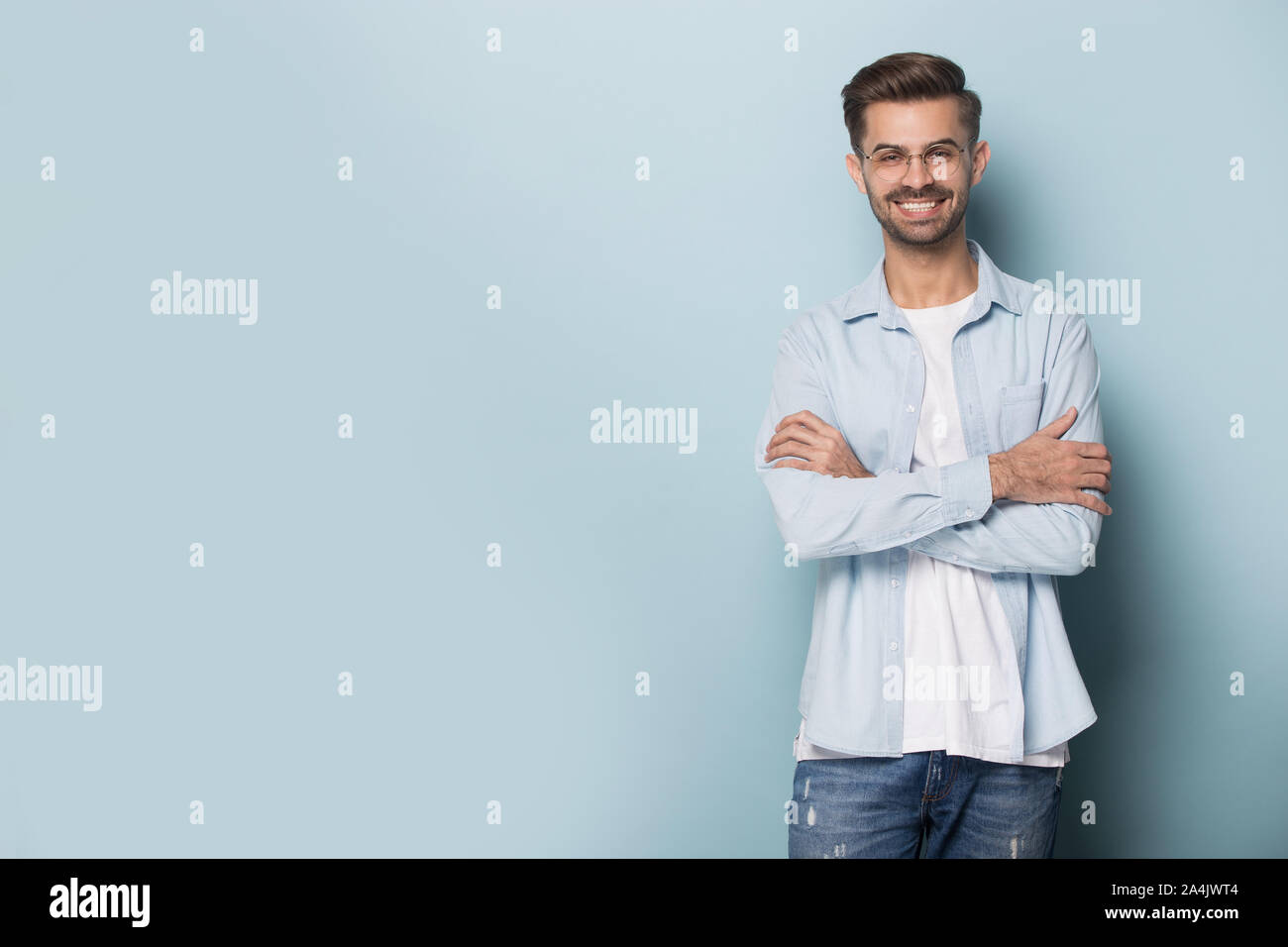 Smiling young man in glasses posing on blue background Stock Photo