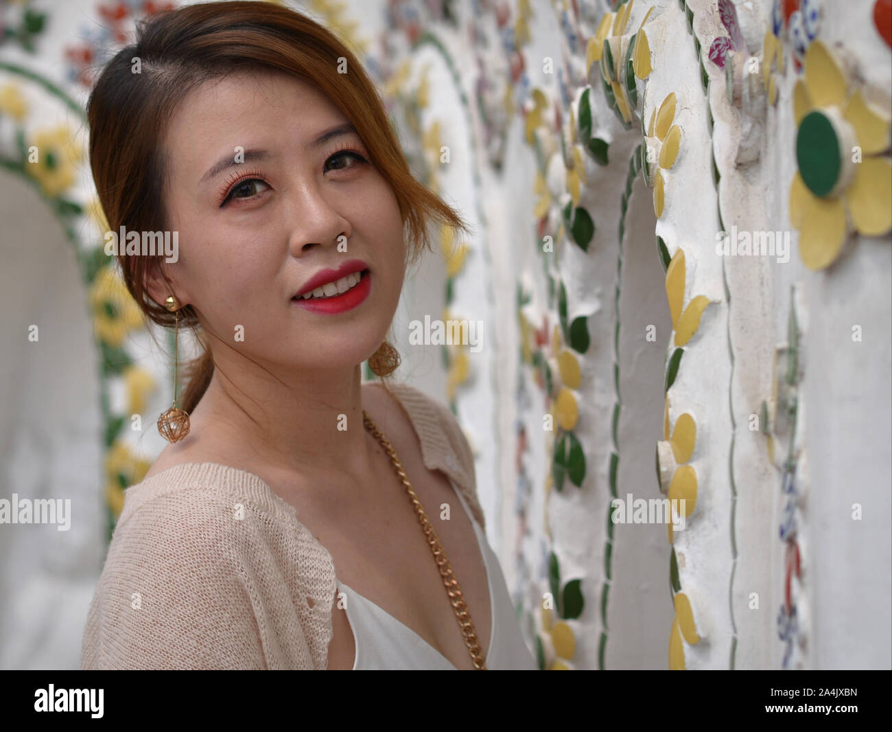 Young Chinese woman (tourist) poses for the camera at Bangkok’s Wat Arun temple. Stock Photo