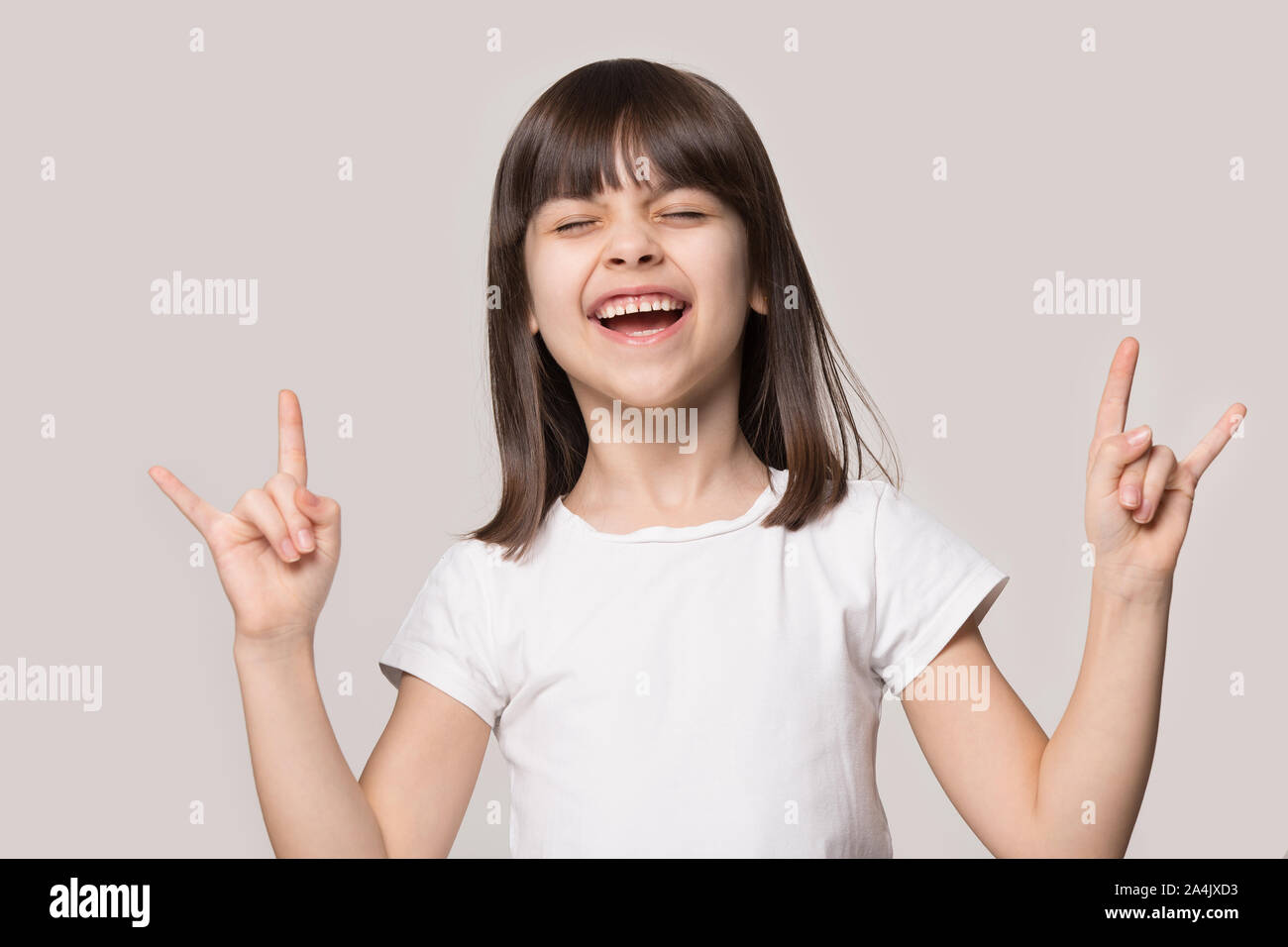 Overjoyed little girl have fun show rock-n-roll gesture Stock Photo