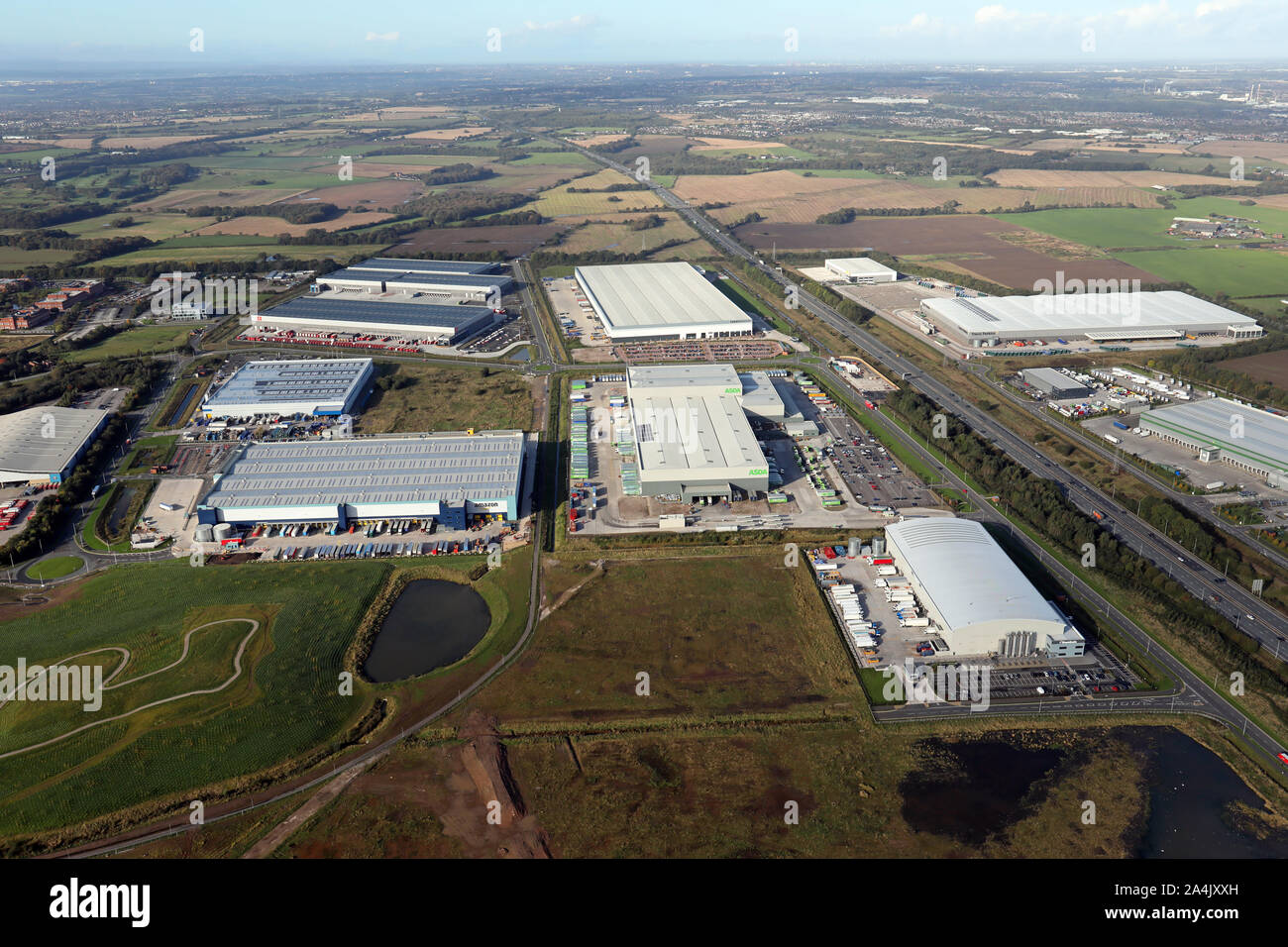 aerial view of new warehouses & logistics hubs on the M62 motorway looking west from junction 8, Burtonwood, Warrington, Cheshire, UK Stock Photo
