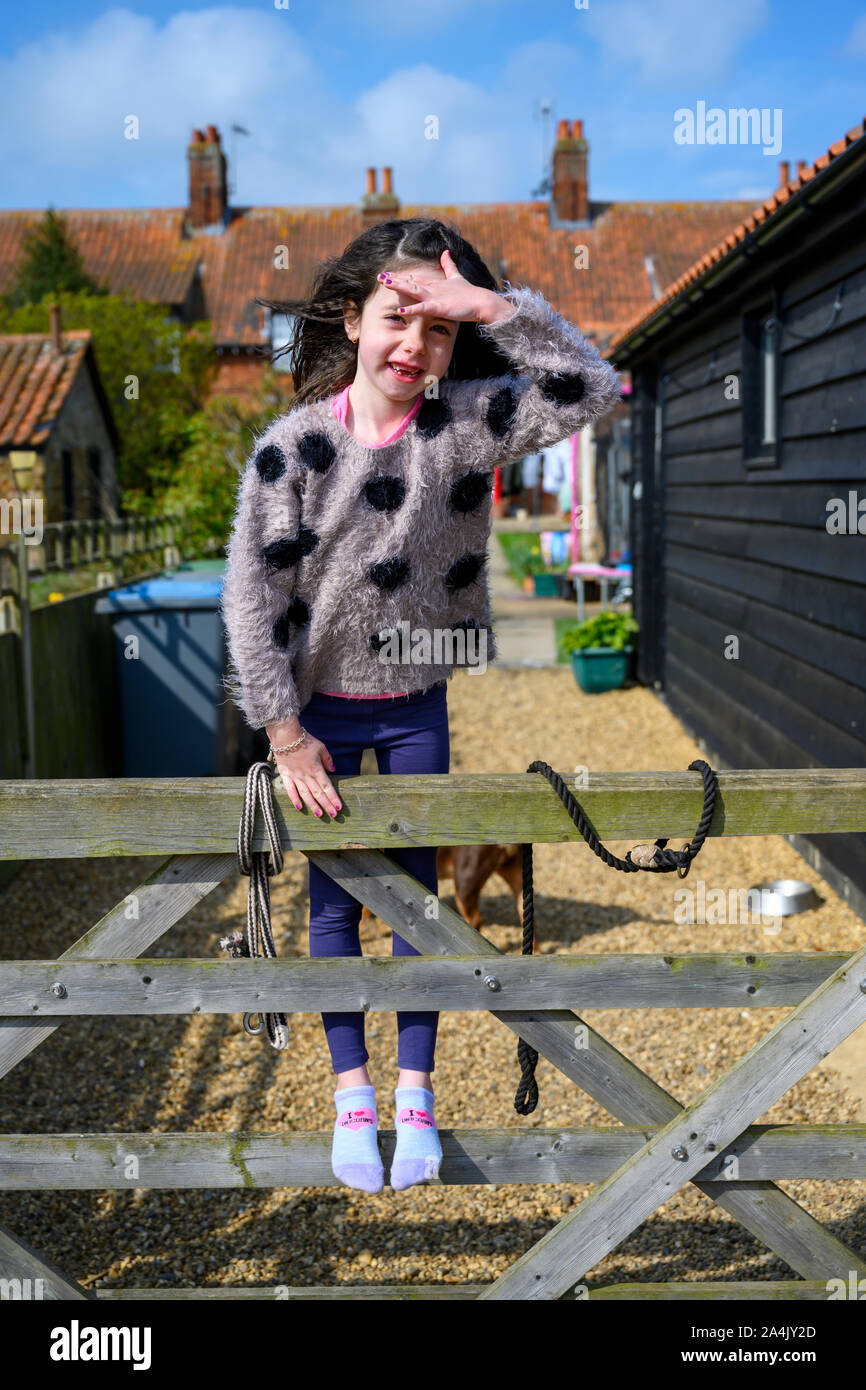 7-year old girl standing on back garden five bared gate Stock Photo