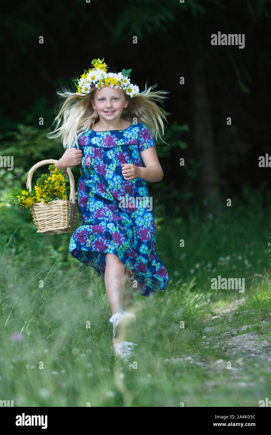 Portrait Of Young Girl Wearing Wreath Running In Meadow Stock Photo