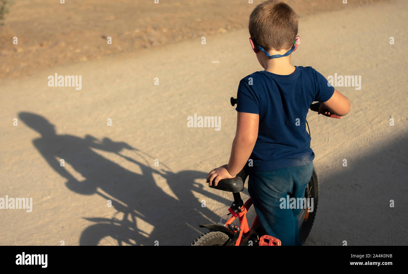 A boy plays in the park with his bike and discovering his shadow Stock Photo