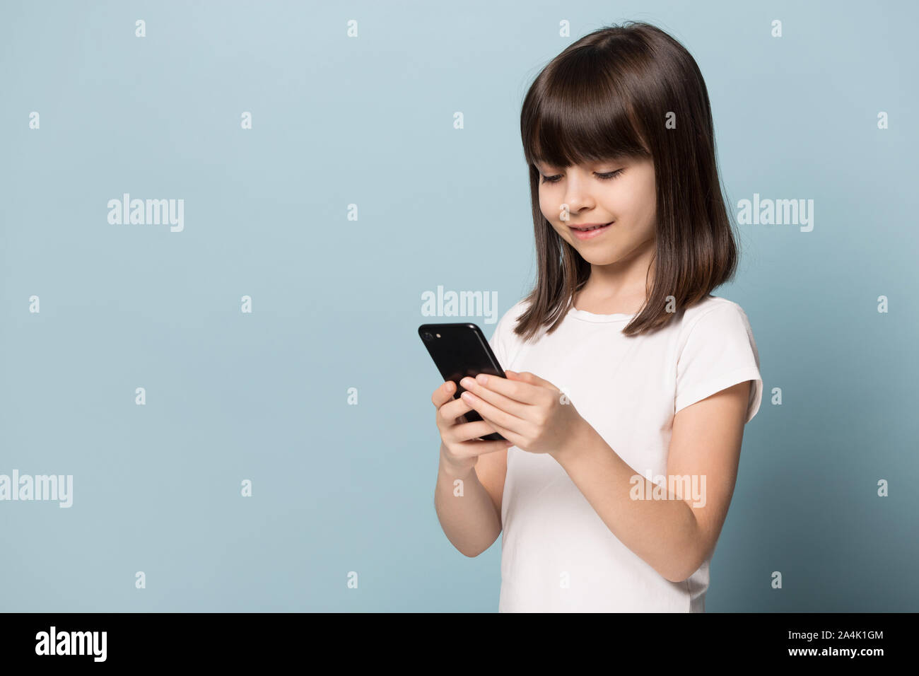 Little girl using modern smartphone watching cartoons Stock Photo