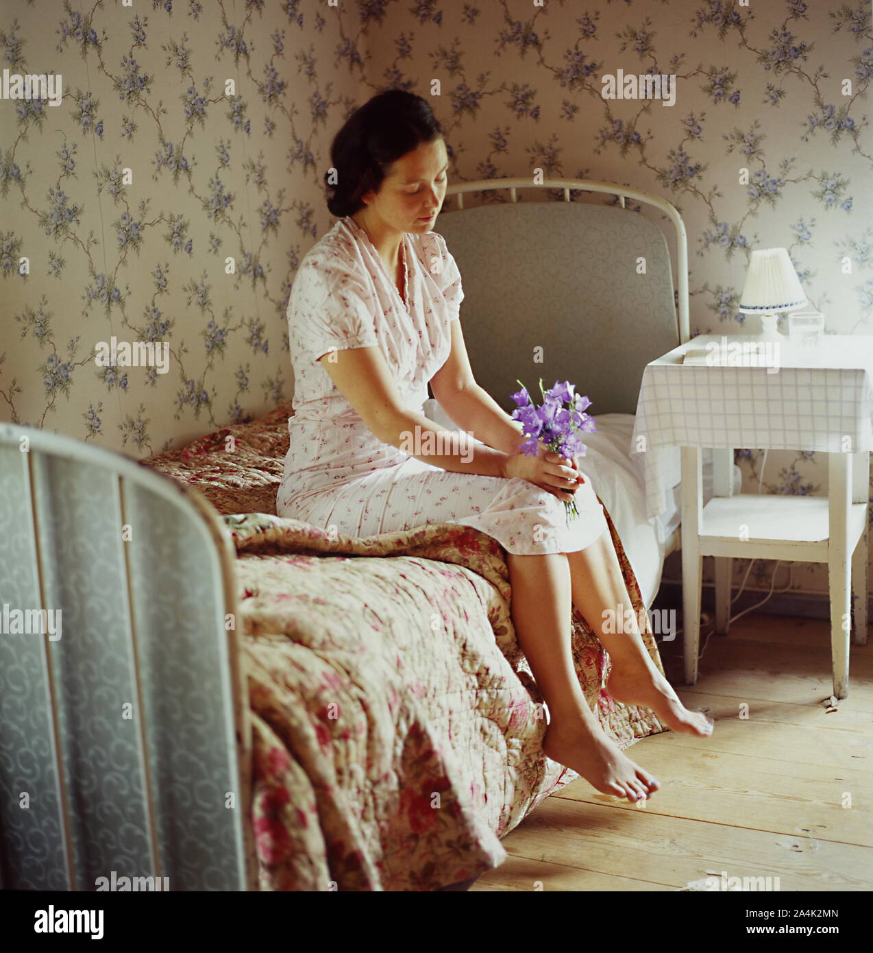 A barefoot woman sitting on the bed. Stock Photo