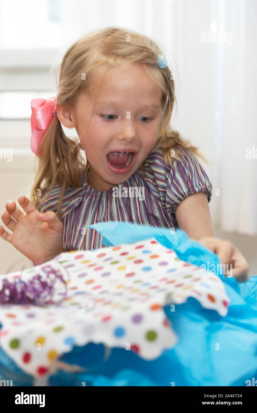 Birthday girl unwrapping presents - wrapping paper - expectations - exited Stock Photo