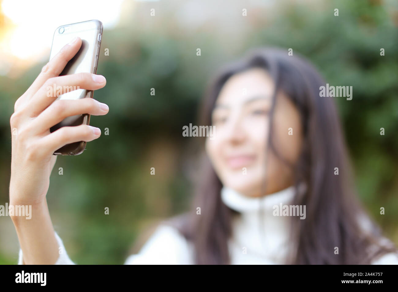 Focus on smartphone, blurred asian girl making selfie. Stock Photo