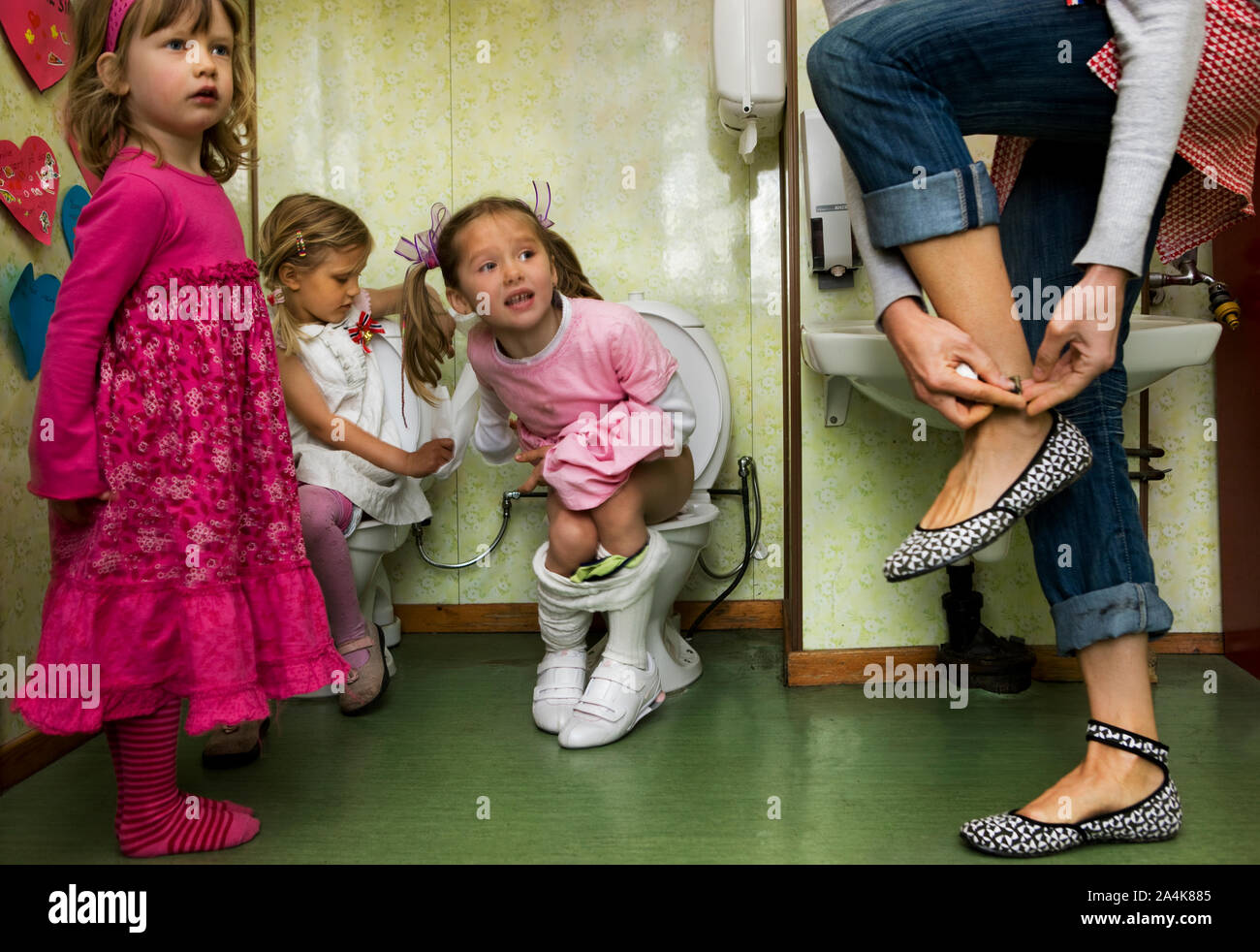 Little girls sitting on toilets Stock Photo