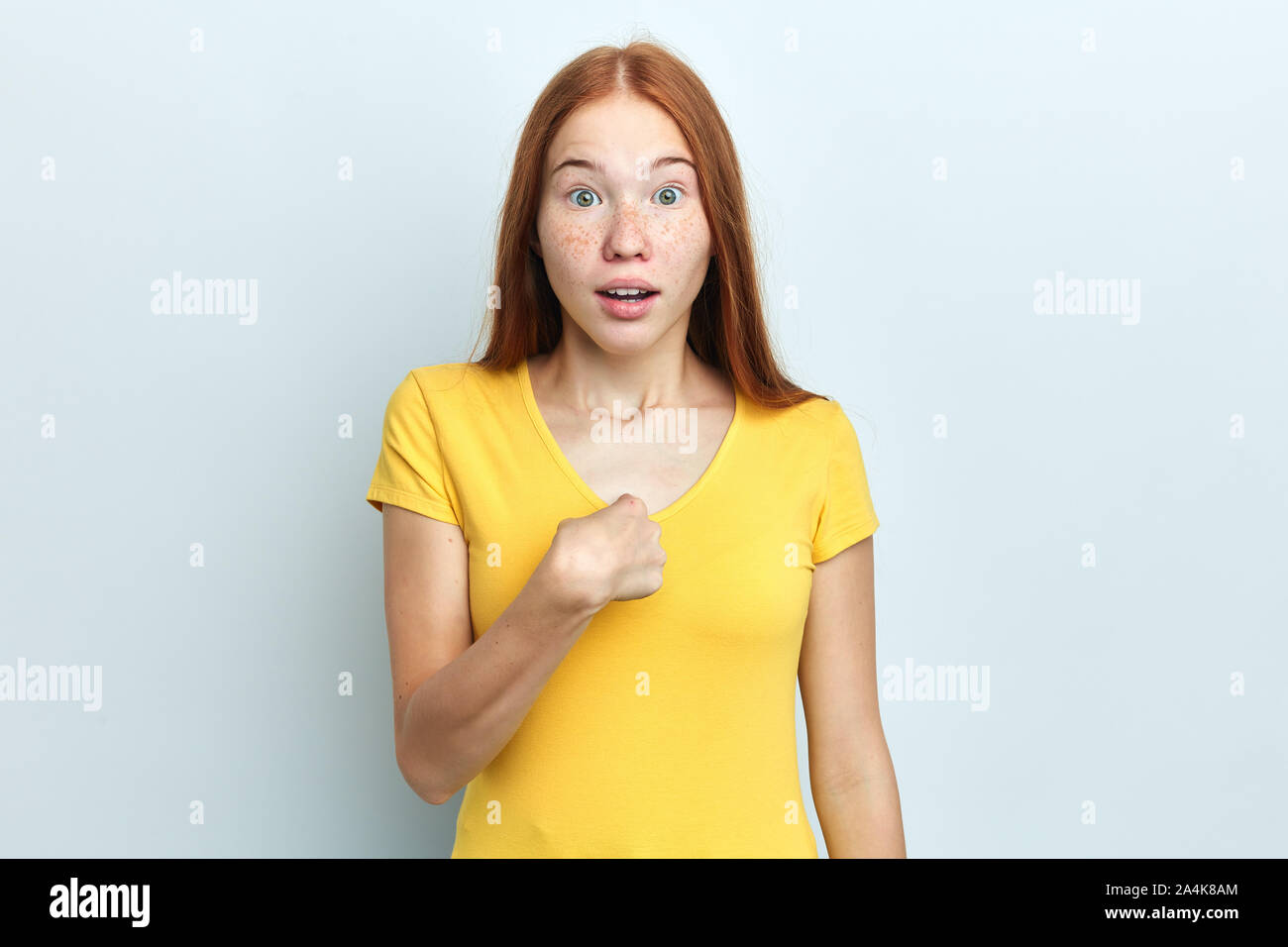 Excuse me Portrait of puzzled serious indignant young woman pointing at herself with finger , feeling confused, standing at studio with white wall Stock Photo