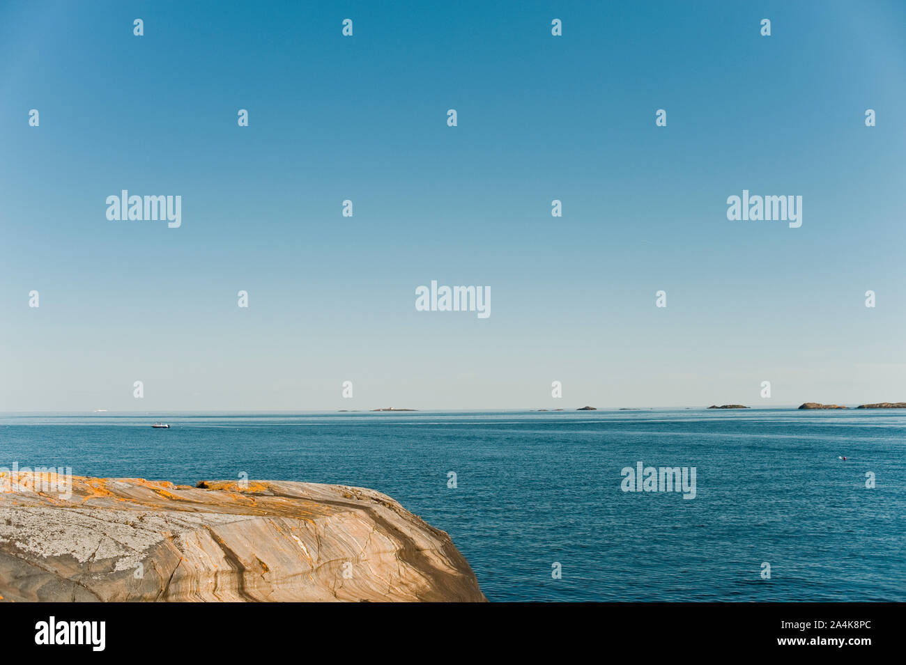 Winded rocks with blue sky and water background Stock Photo - Alamy