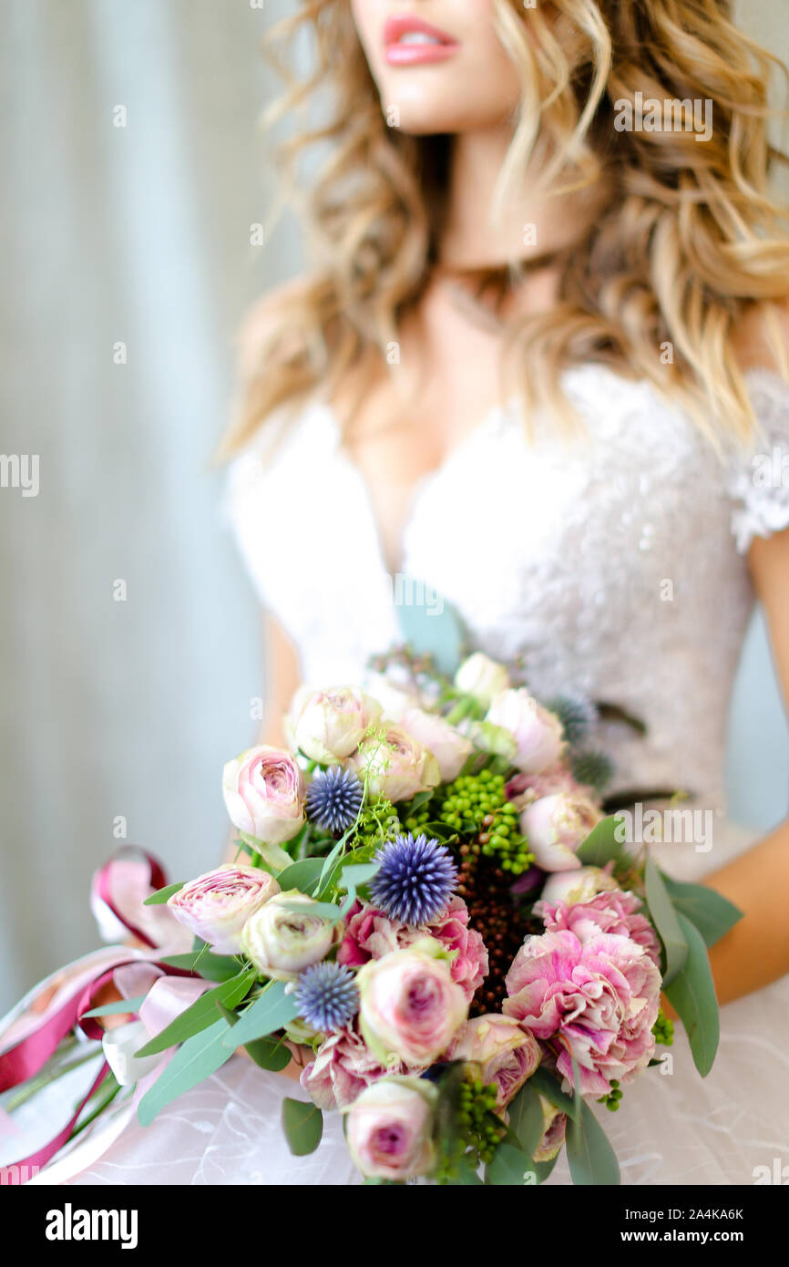 Young caucasian bride wearing white dress with bouquet at photo studio. Stock Photo