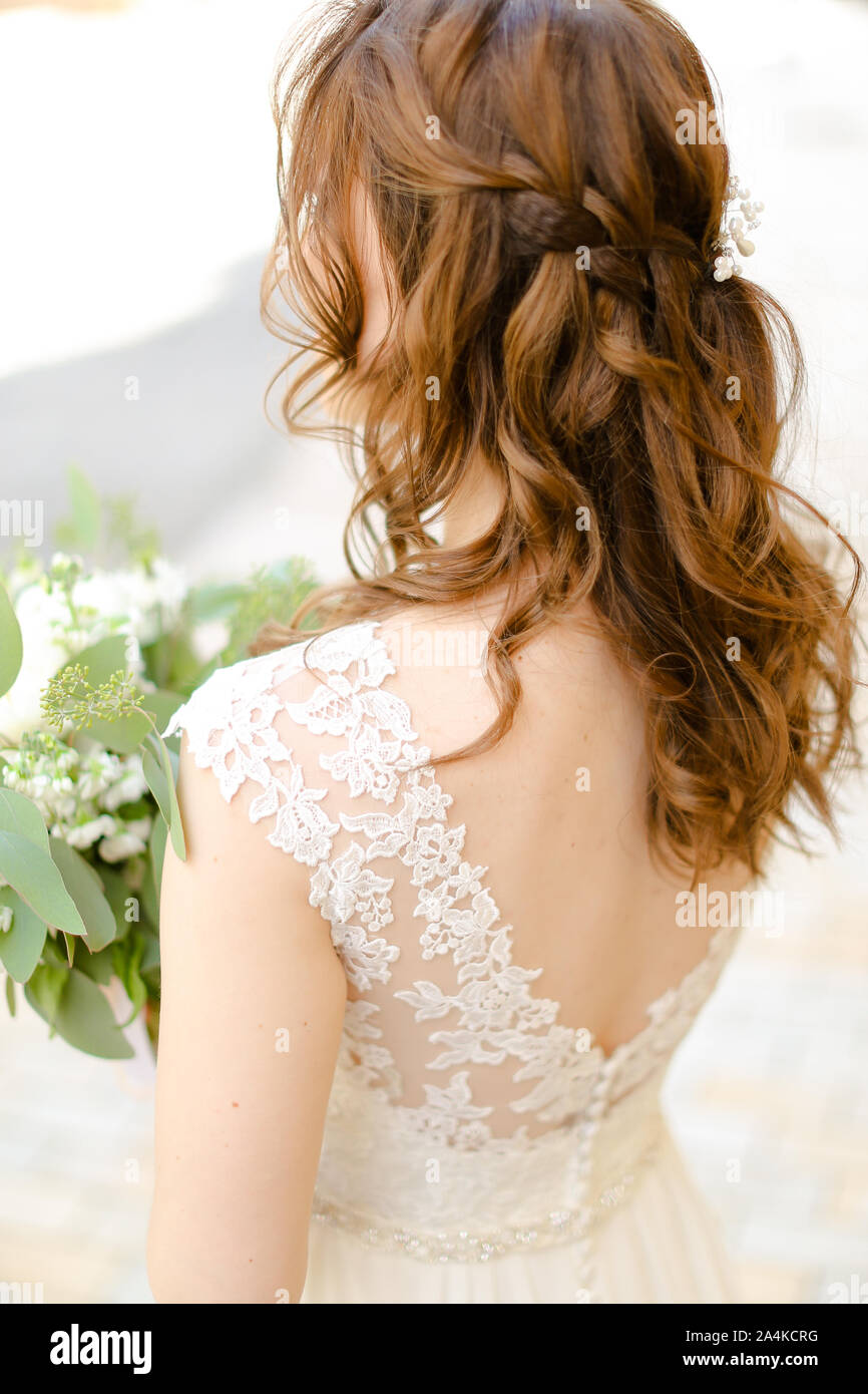 Back view of curls hair do for bride keeping flowers Stock Photo - Alamy
