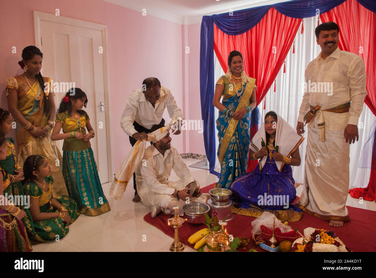 Hindu family in London UK celebrate their 16 year old daughters coming of age party. Ritushuddhi, also called as Ritu Kala Samskara, Coconut milk is poured onto her head by her brother, who sits of floor with her. This  ritual symbolises health and prosperity, family members stand by her side. Mitcham south London UK HOMER SYKES Stock Photo