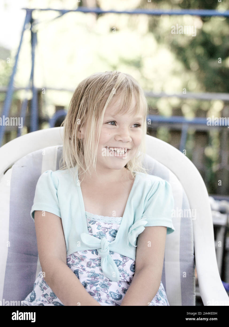 Little girl smiling, sitting in a chair Stock Photo - Alamy