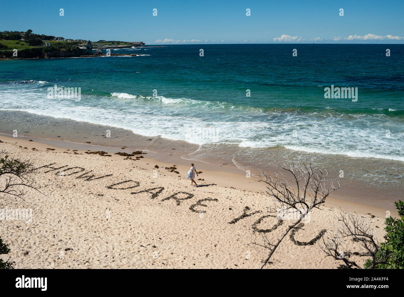 24.09.2019, Sydney, New South Wales, Australia - A woman walks along Coogee Beach where the quote How Dare You? is written in the sand. Stock Photo