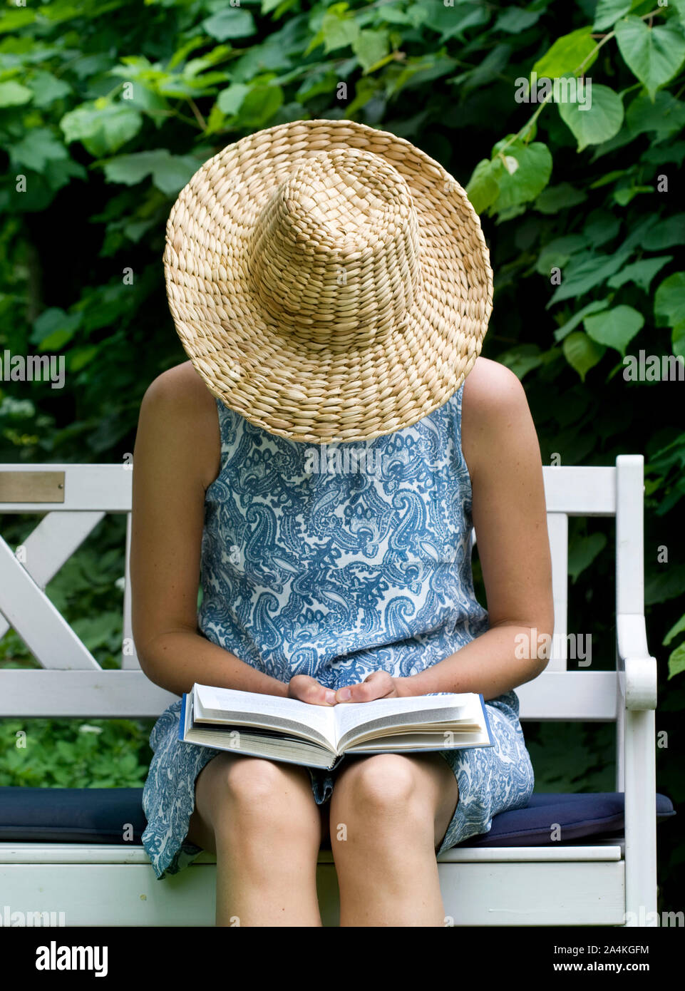 Woman on bench wearing straw hat Stock Photo