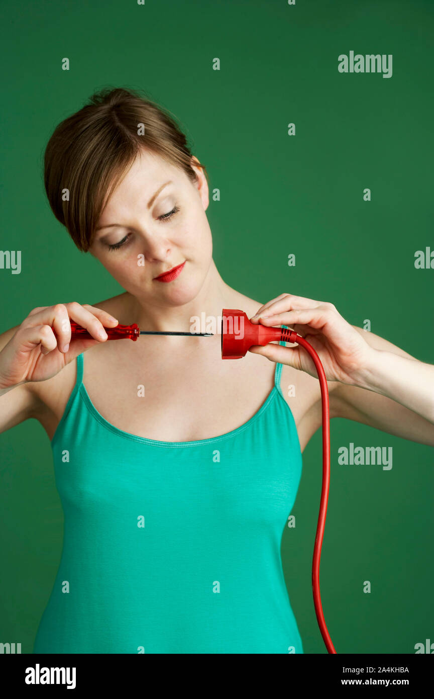 Woman with screwdriver and electrical plug Stock Photo