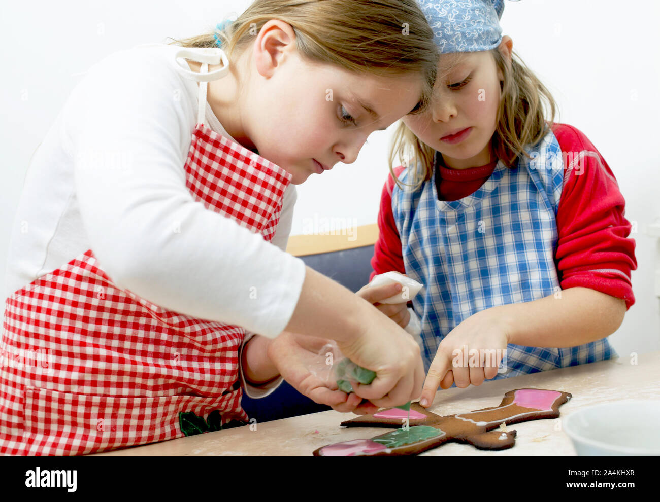 Two girls with headscarf and apron making homemade gingerbread. Stock Photo