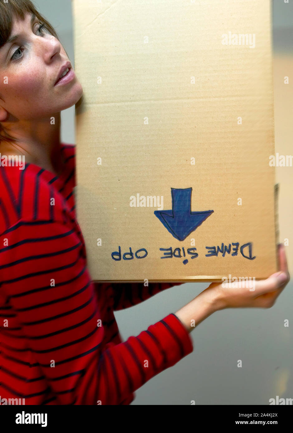 A woman carrying a carton box upside-down Stock Photo
