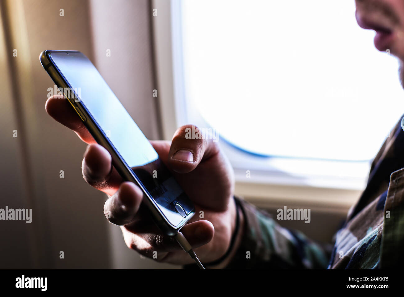 Closeup man using smartphone near window in airplane. Stock Photo
