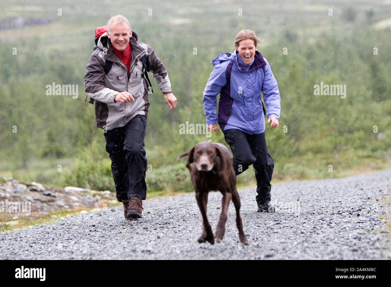 Portrait Of Couple Running After Dog Stock Photo