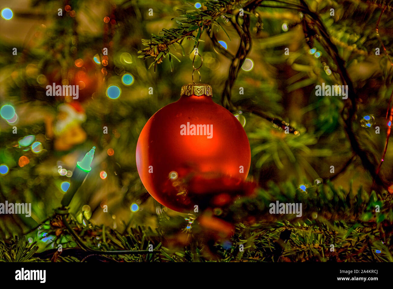 Holiday background with red ball in tree with lights Stock Photo - Alamy