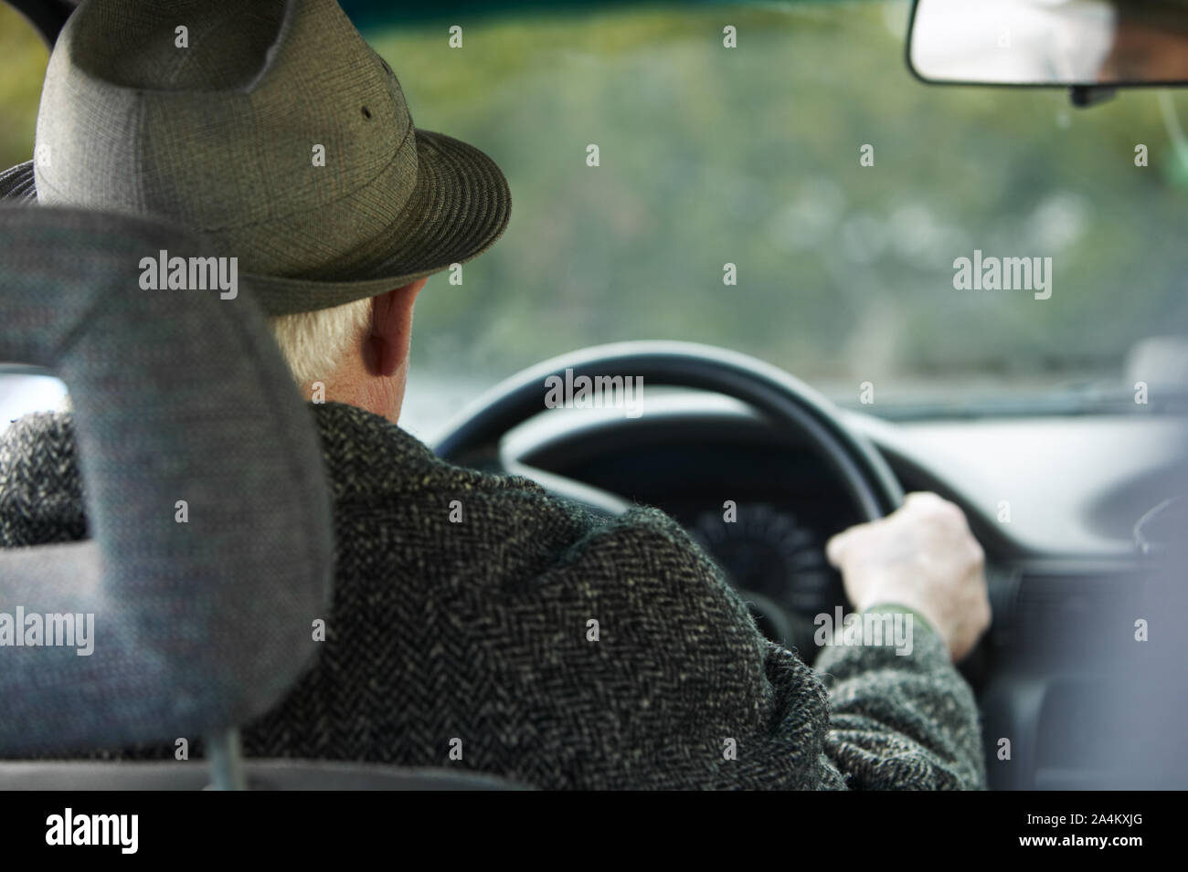 An old man with hat/ bowler driving a car. Old age - senior Stock Photo