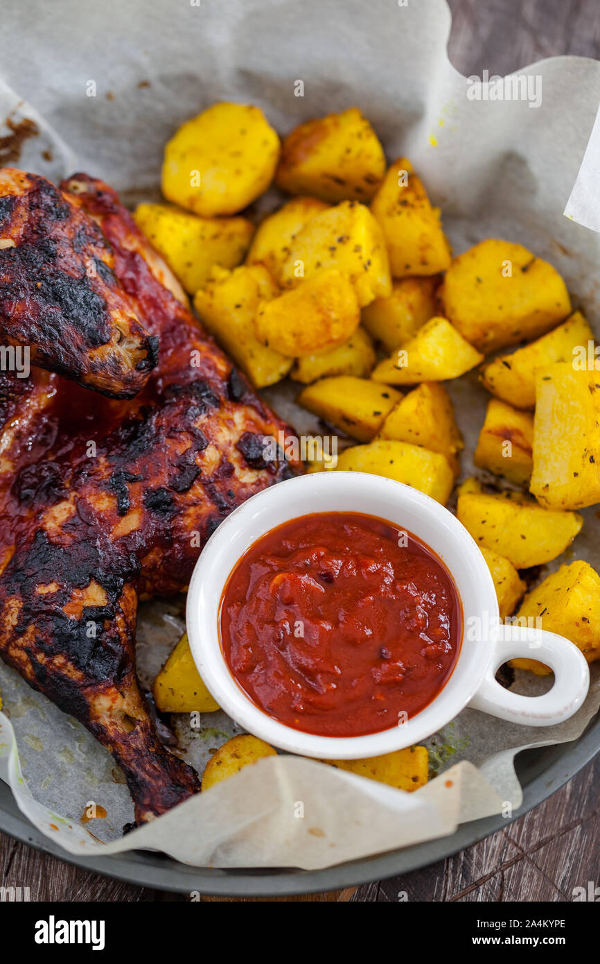 Roasted chicken with potatoes and red sauce Stock Photo - Alamy