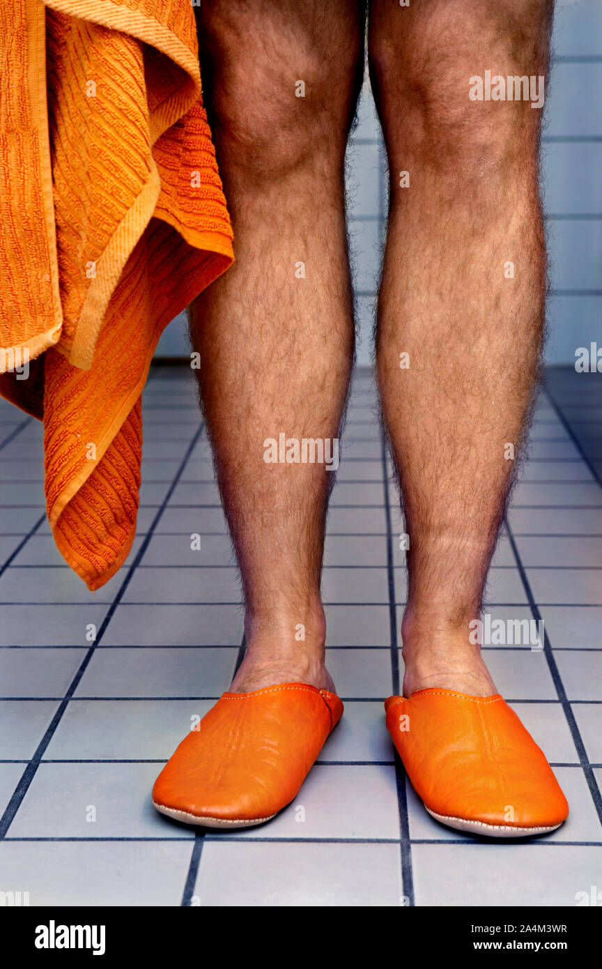 Hairy legs and orange slippers Stock Photo