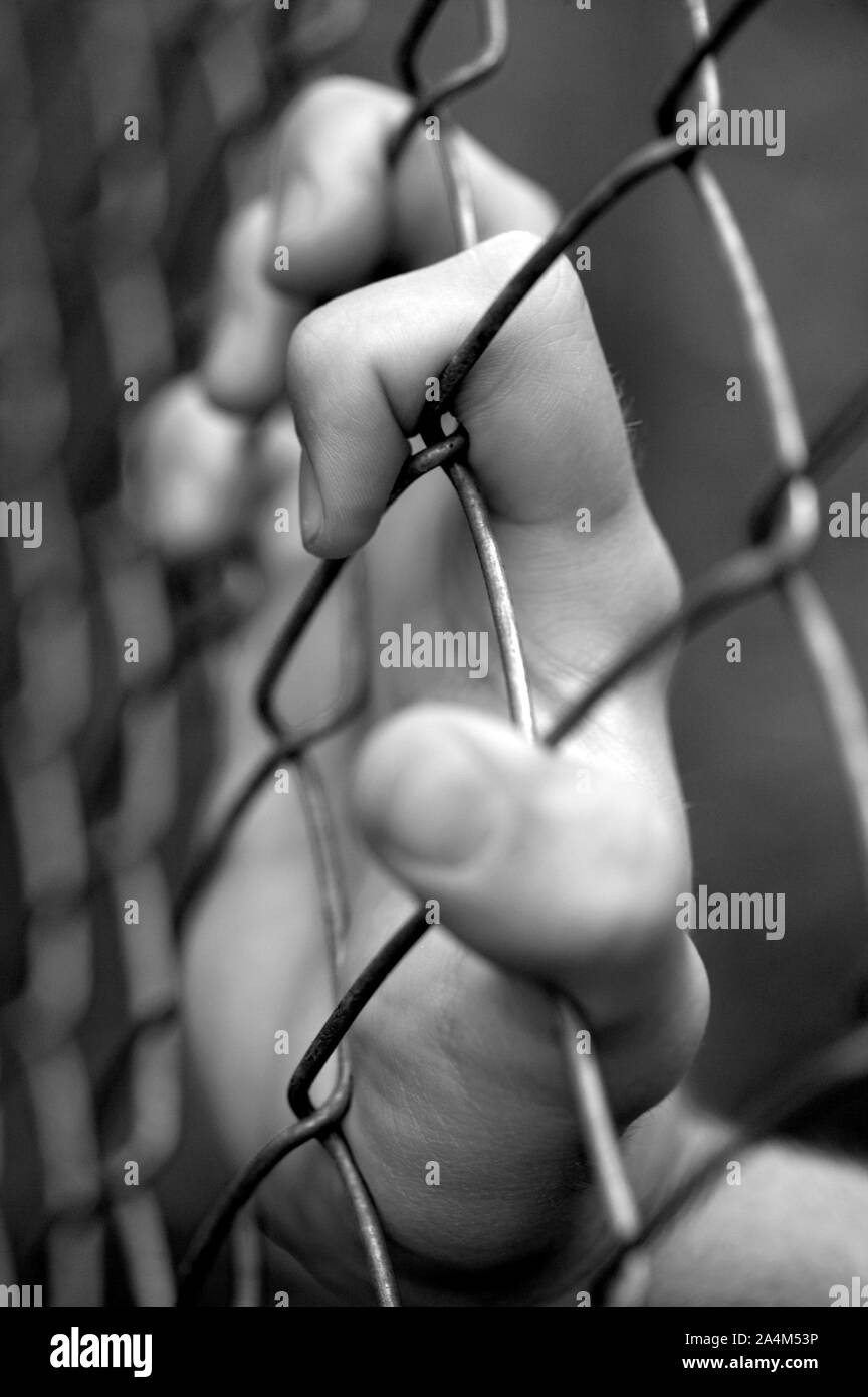Behind a wire fence - locked up - desperation Stock Photo