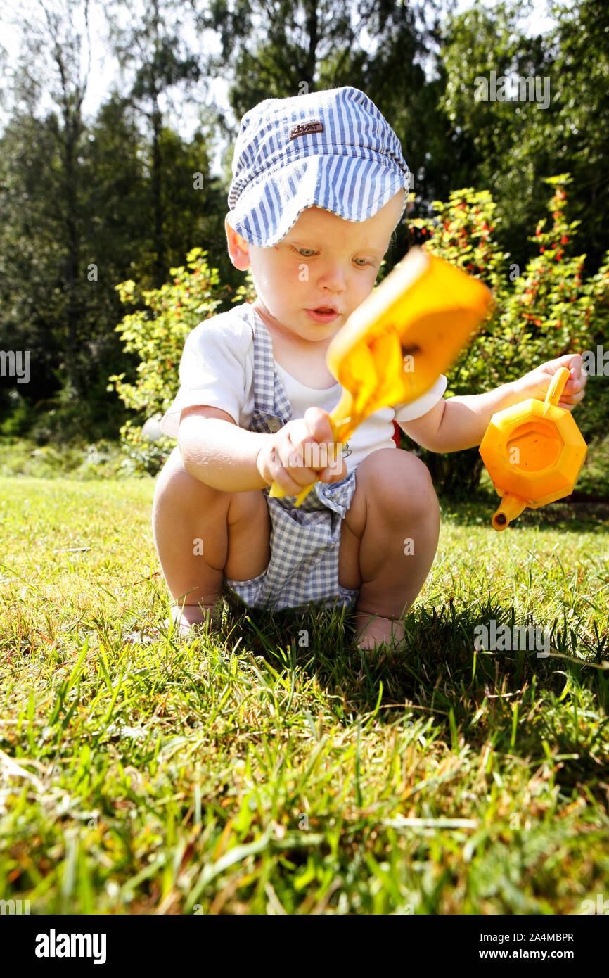 Boy with toys - spade and teapot - squat Stock Photo - Alamy