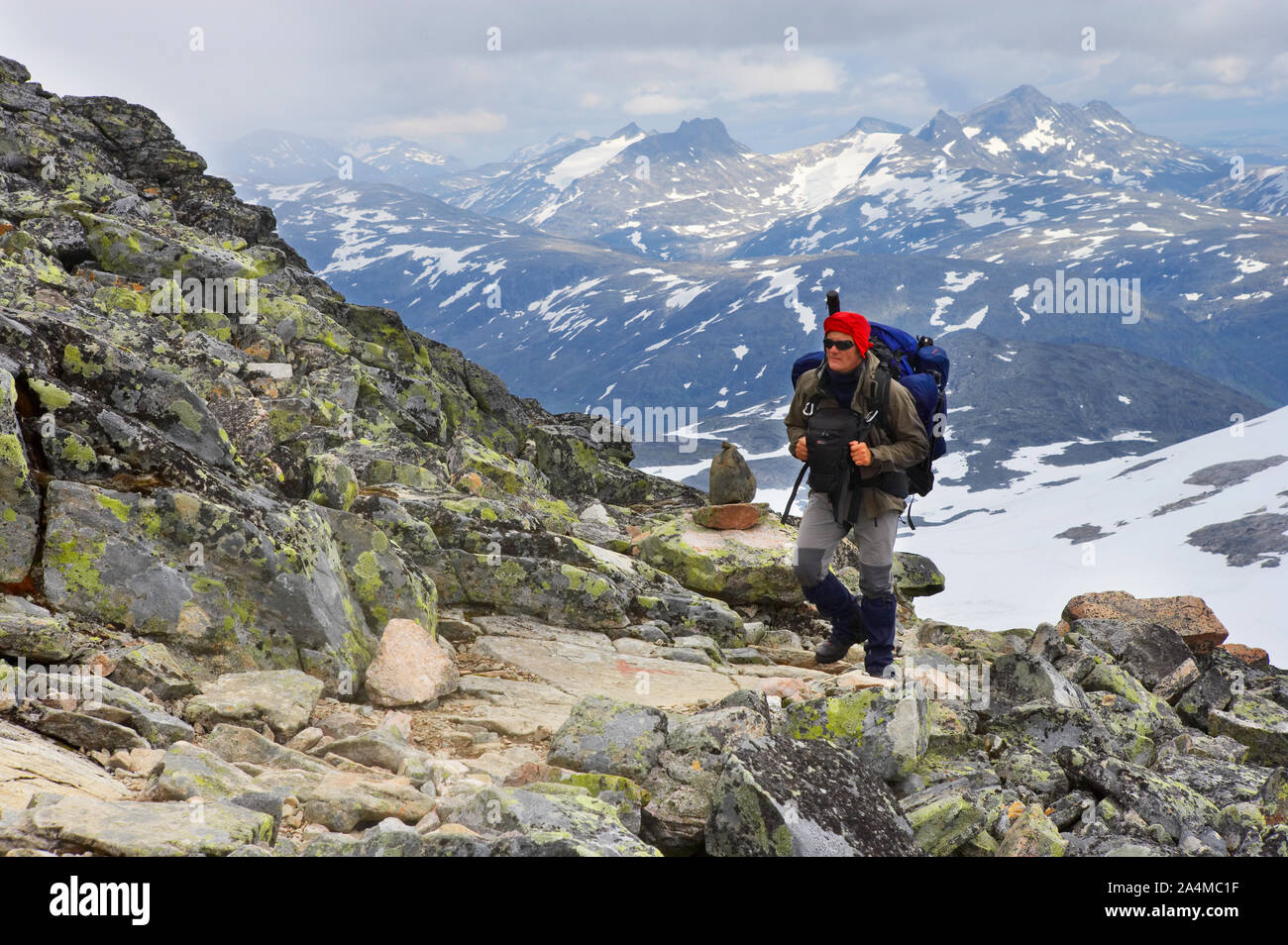 Hiker on the way to the mountain top of Fannaråken, Sognefjellet in Jotunheimen, Norway. Stock Photo