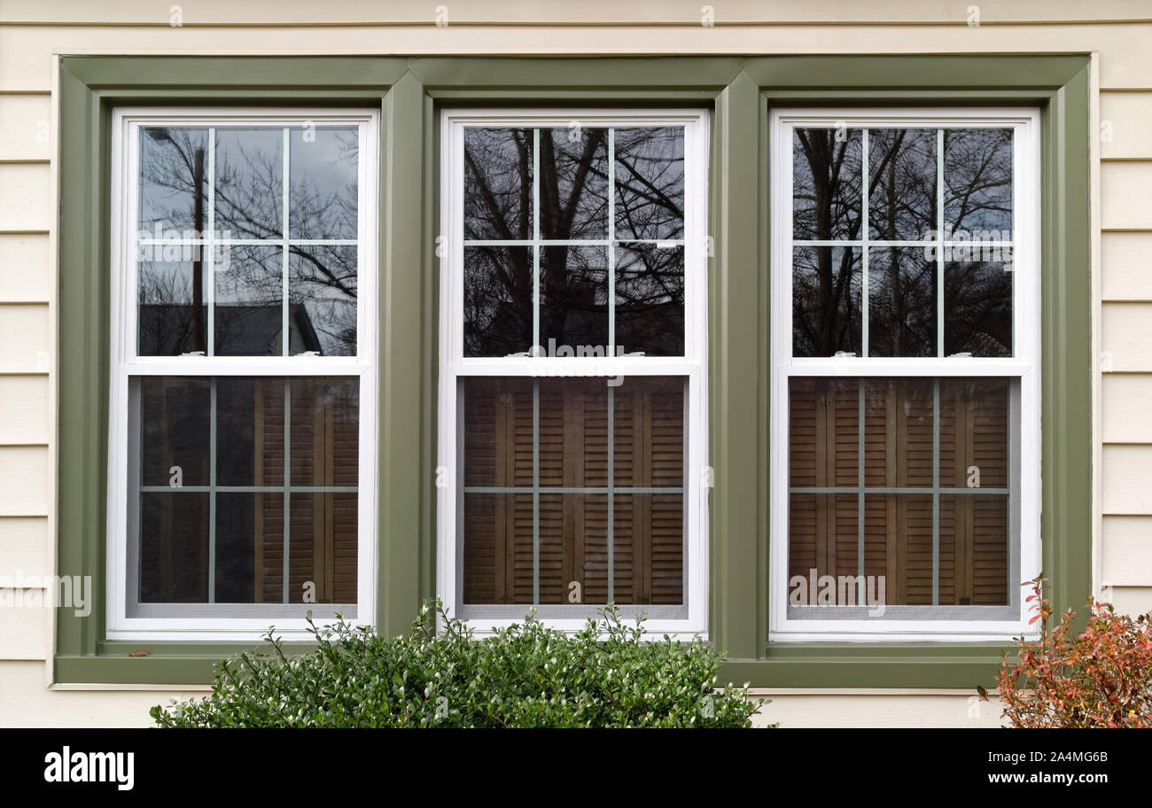 Three new replacement windows with green trim on front of house. Horizontal. Stock Photo