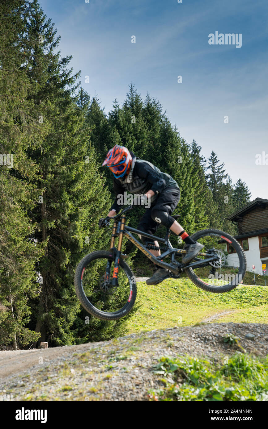 Savognin, GR / Switzerland, - 12 October, 2019: downhill mountain biker jumping high and riding hard in Lenzerheide in the Swiss Alps Stock Photo
