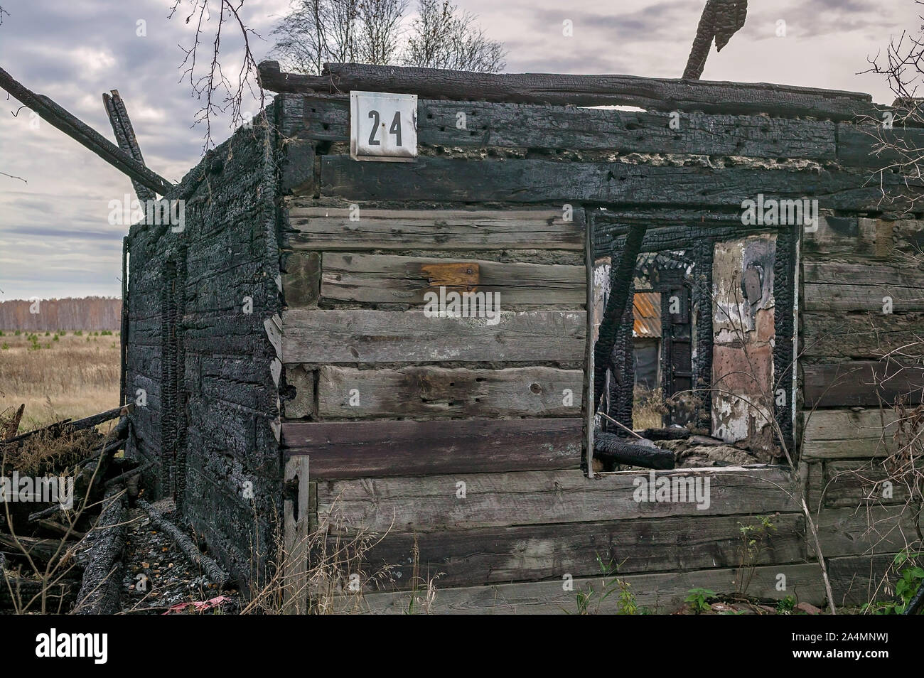 Burnt wooden house number 24. Destroyed roof and windows, charred walls. Horizontal shot Stock Photo