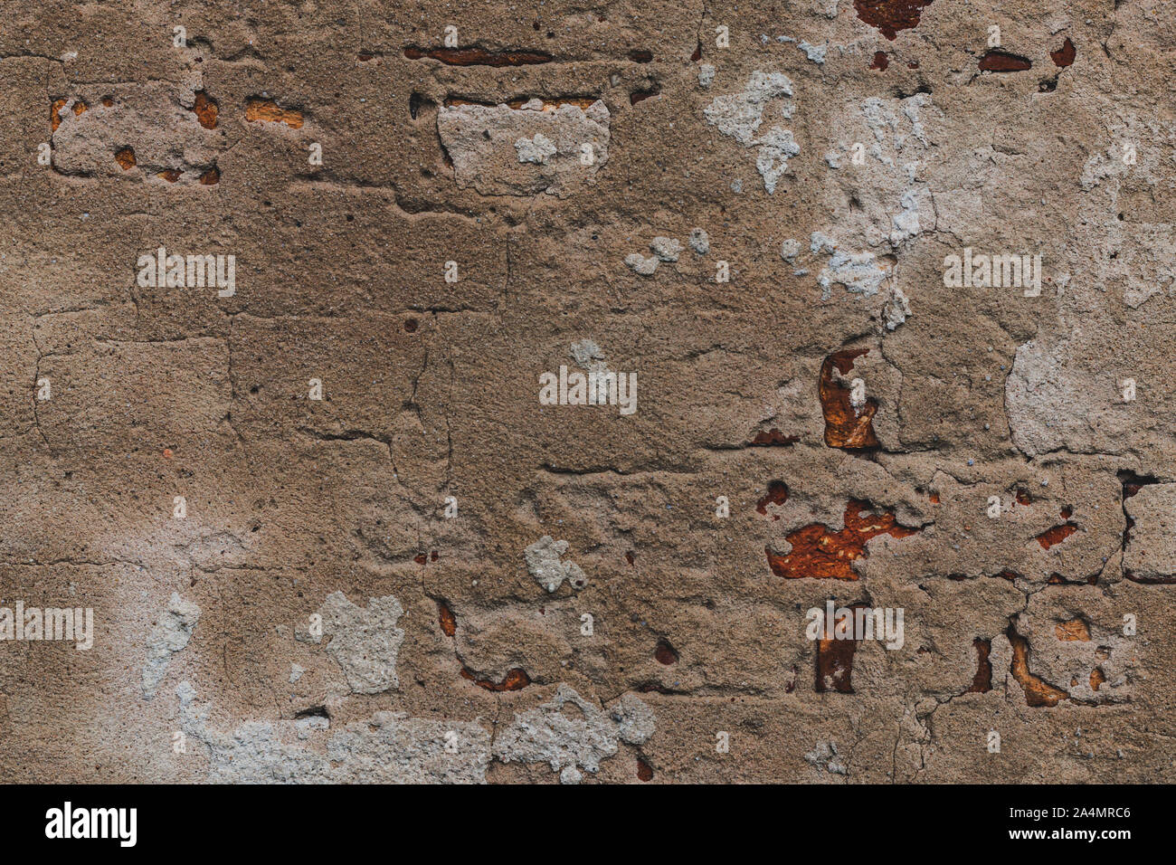 Old ruined and cracked wall made of red bricks with remains of plaster. Stock Photo