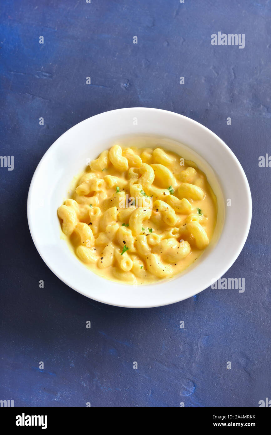 Macaroni and cheese in white bowl on blue stone background Stock Photo