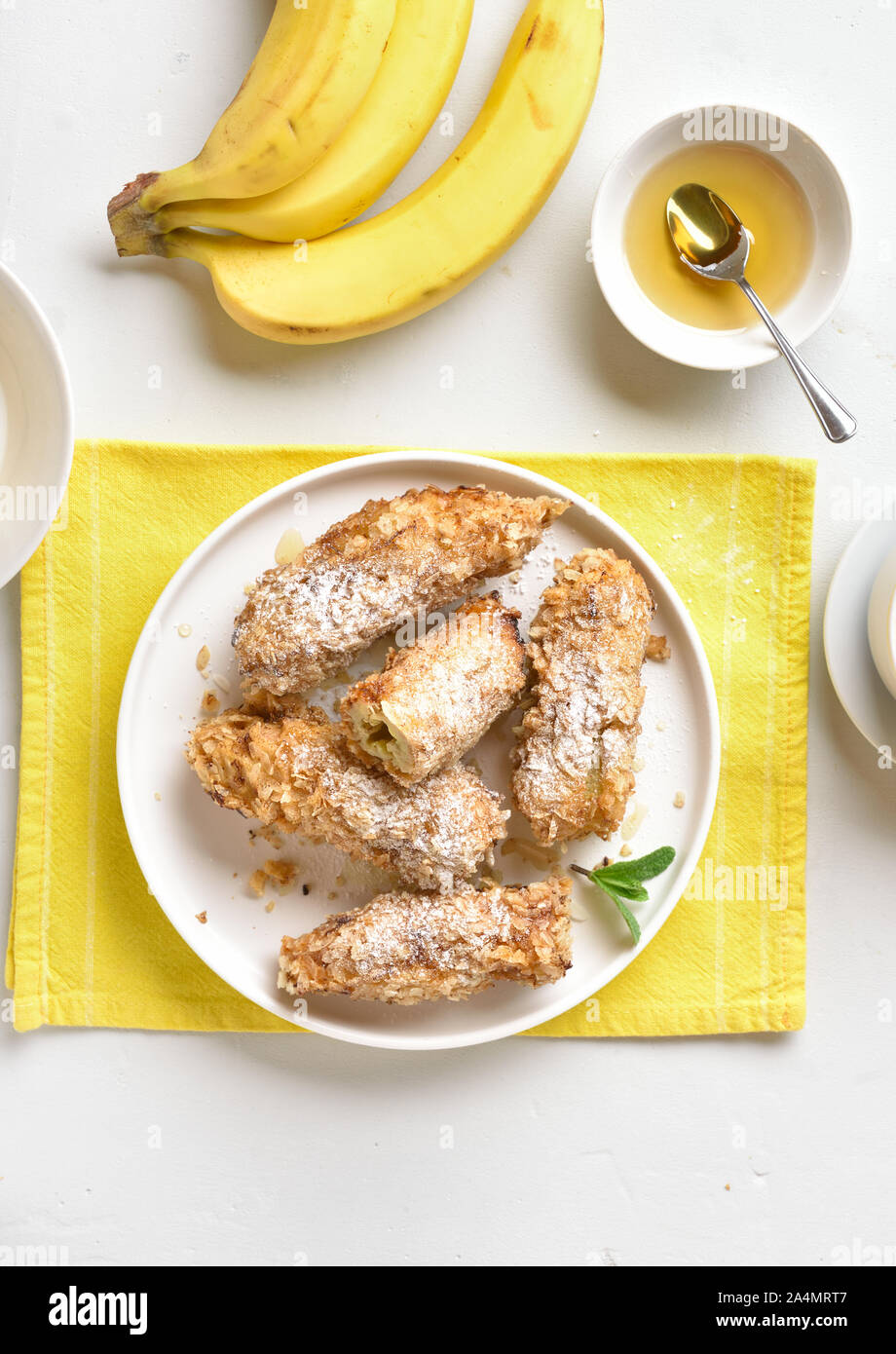 Deep fried bananas on plate over white stone background. Tasty dessert