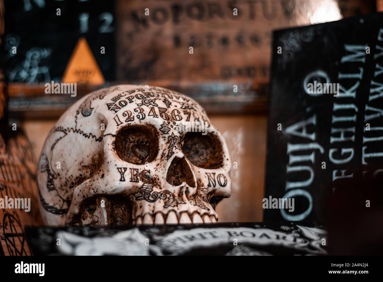 Talking board and planchette, also known as the Ouija board, used for communicating with the dead and other spirits. Halloween background. White skull. Stock Photo